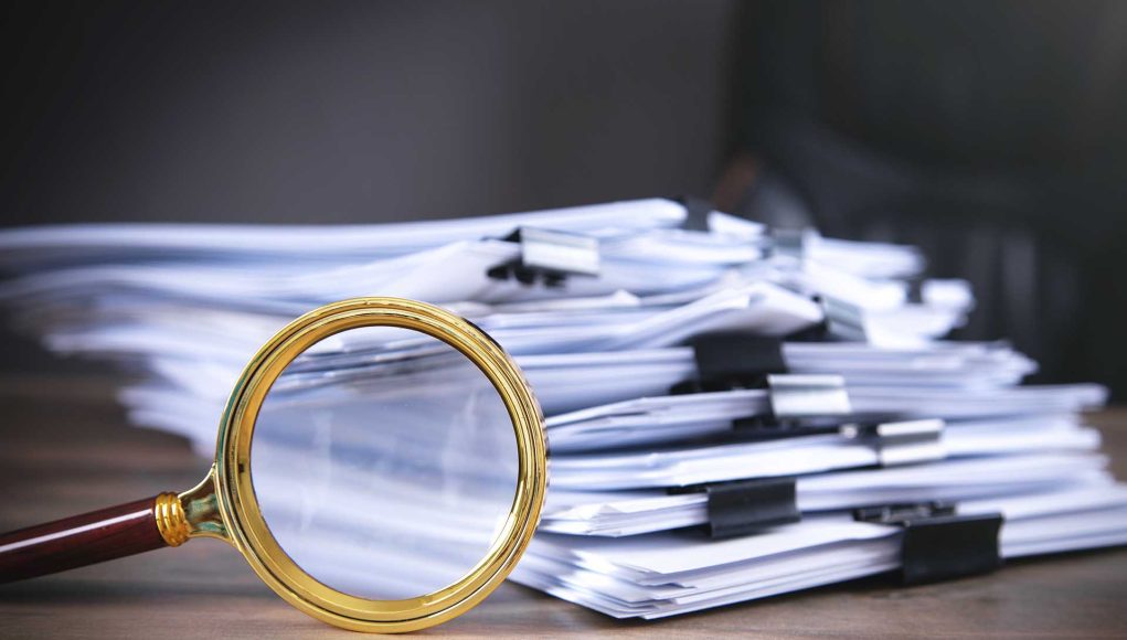 Stack of documents and magnifying glass on the table.